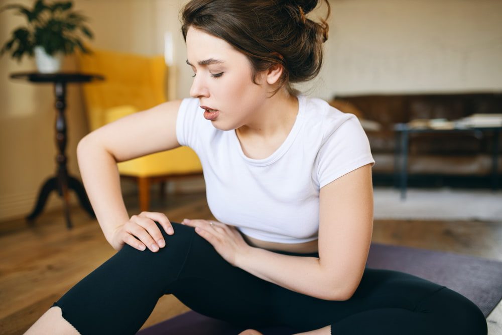 Comment éviter les courbatures : une femme est assise sur le sol