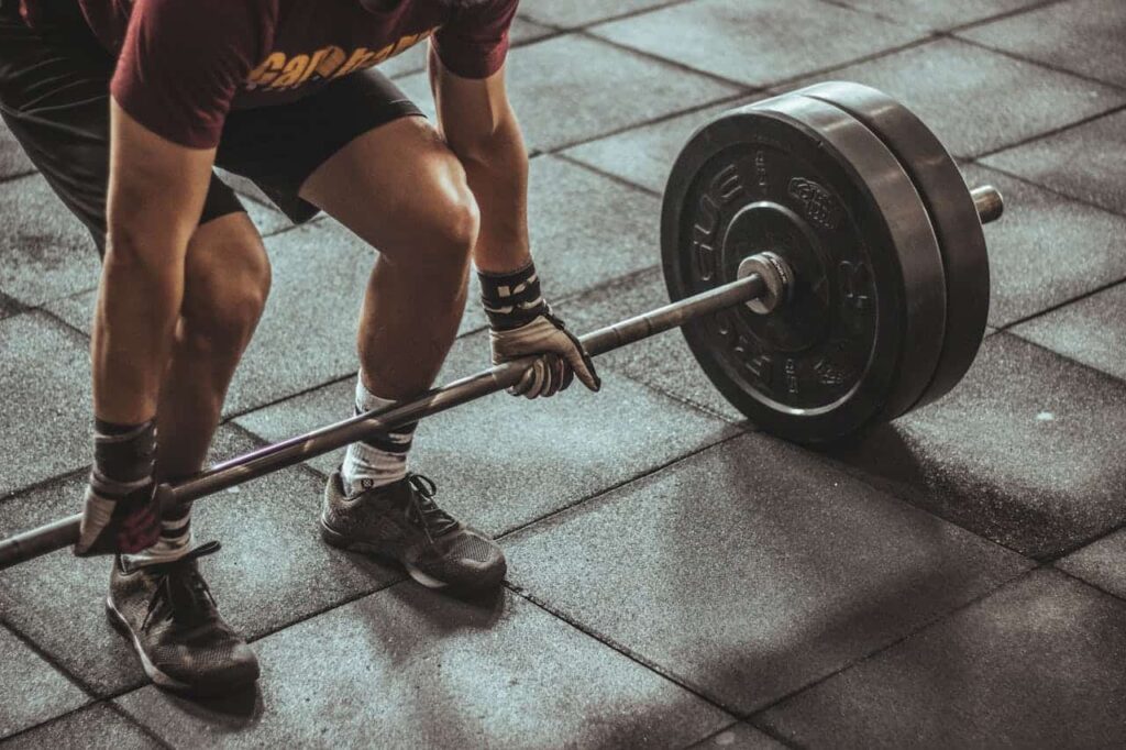 Musculation avec ou sans gants : un homme soulève une barre d'haltère