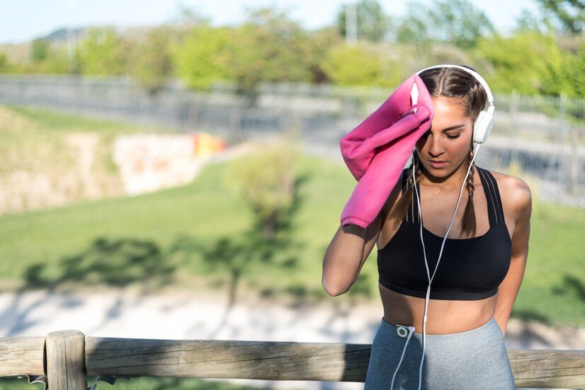 Les bienfaits de la transpiration pendant le sport : une femme est en train d'essuyer sa sueur avec une serviette